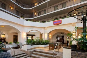 Un atrio de varios niveles con un restaurante, zonas de estar y una escalera.
