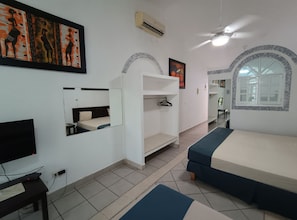 Habitación de hotel con cama, televisión, espejo, armario y una pared decorada con obras de arte.