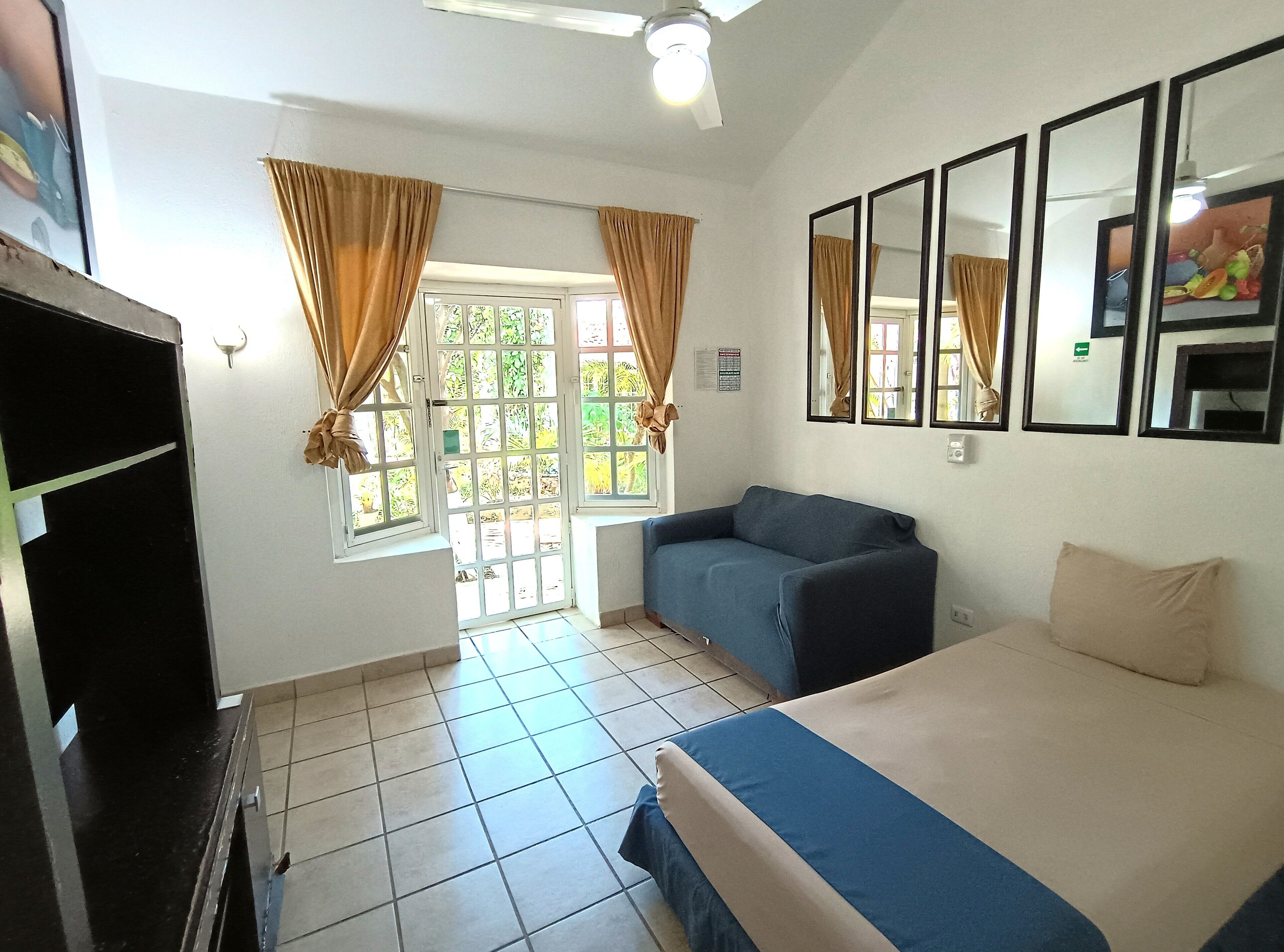 A room with a bed, a sofa, a TV, and a window with curtains.