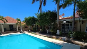 Une piscine entourée de palmiers et un bâtiment doté d’un toit en tuiles.