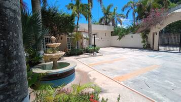 A courtyard with a fountain, palm trees, and a gated entrance.