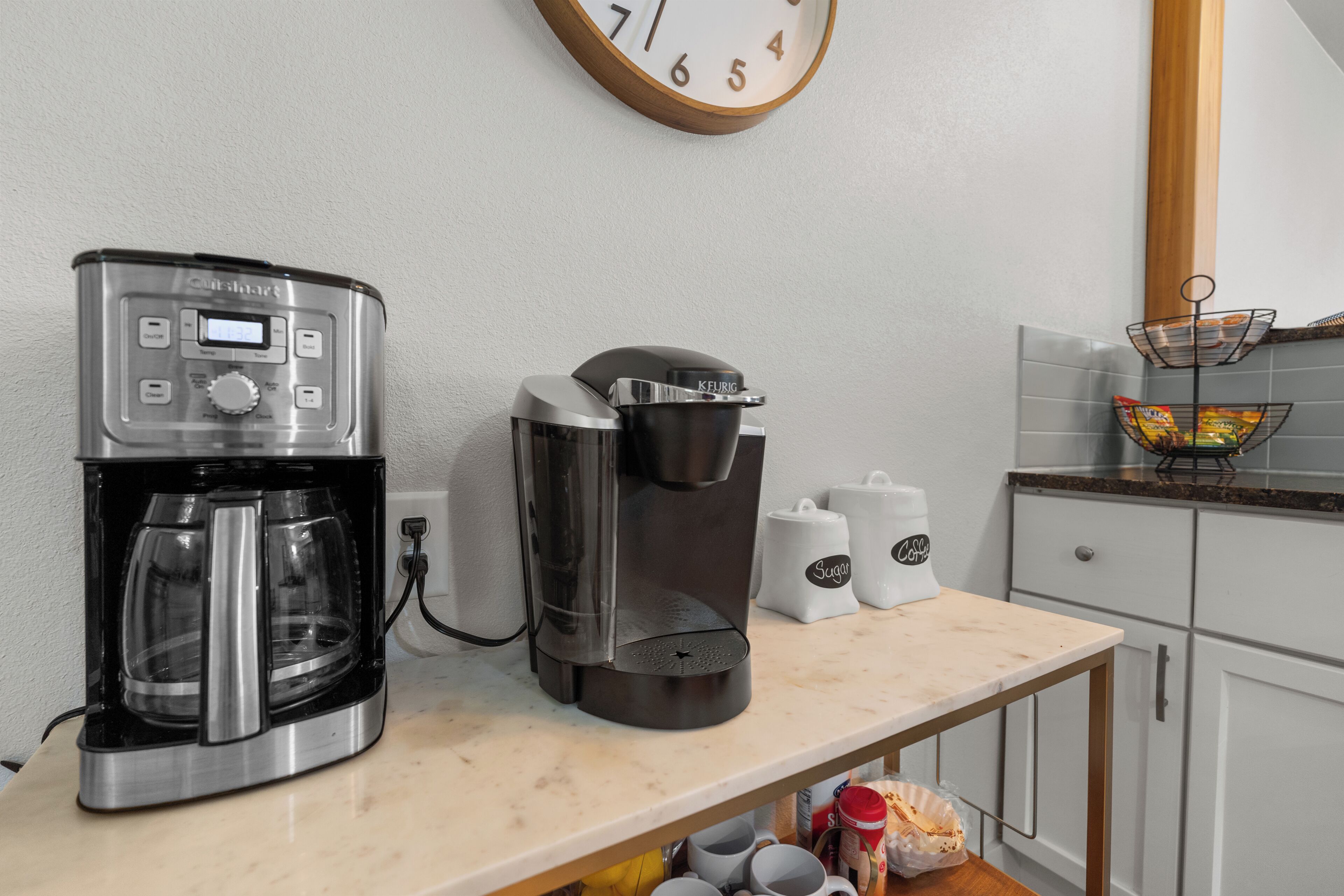 A kitchen with a coffee maker, a clock, and a coffee station.