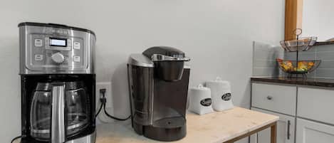 Una cocina con cafetera, un reloj y una zona de café.