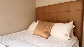 A bed with a tufted headboard, two pillows, and a white bedspread.