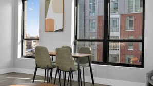 A modern interior with a dining area, large windows, and a view of a cityscape.