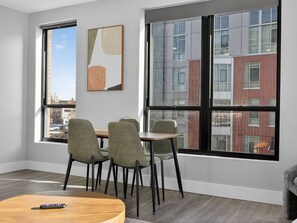 A modern interior with a dining area, large windows, and a view of a cityscape.