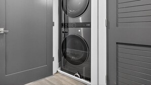A laundry room with two stacked washing machines, a door, and a wall with horizontal lines.