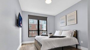 A bedroom with a bed, a window, and a mounted television.