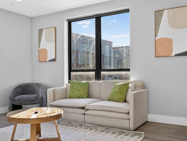 A modern living room with a sofa, a round coffee table, and artwork on the walls.