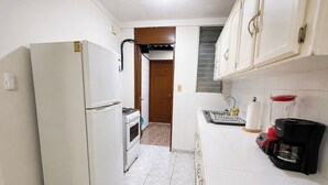 A compact kitchen with a refrigerator, oven, and a coffee maker.