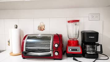 Eine Küche mit einem roten Toaster, einem roten Mixer und einer schwarzen Kaffeemaschine auf einer weißen Fliesenarbeitsplatte.