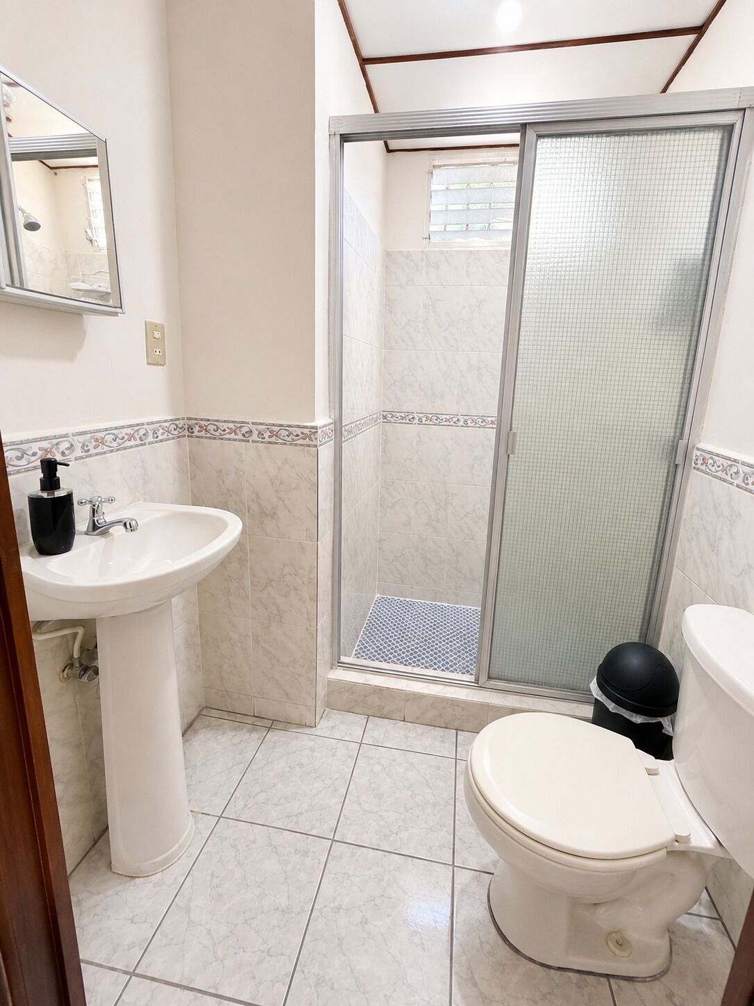 A bathroom with a white sink, toilet, and shower area.