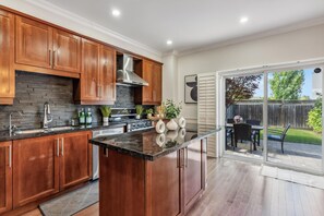 A modern kitchen with wooden cabinets, a black countertop, and a central island. - Luxurious townhome ideal for families, business travelers, and long stays. (Toronto)