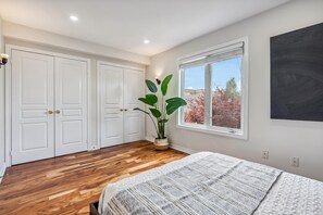 A bedroom with a large bed, a potted plant, and a window with a view of trees. - Luxurious townhome ideal for families, business travelers, and long stays. (Toronto)