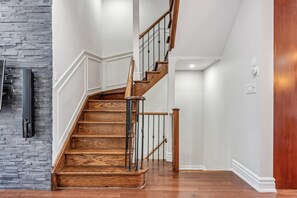 A wooden staircase with a handrail, leading to a landing with a white wall and a door. - Luxurious townhome ideal for families, business travelers, and long stays. (Toronto)