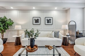 A modern living room with a white sofa, two side tables with lamps, a coffee table with a vase, and two framed pictures on the wall. - Luxurious townhome ideal for families, business travelers, and long stays. (Toronto)