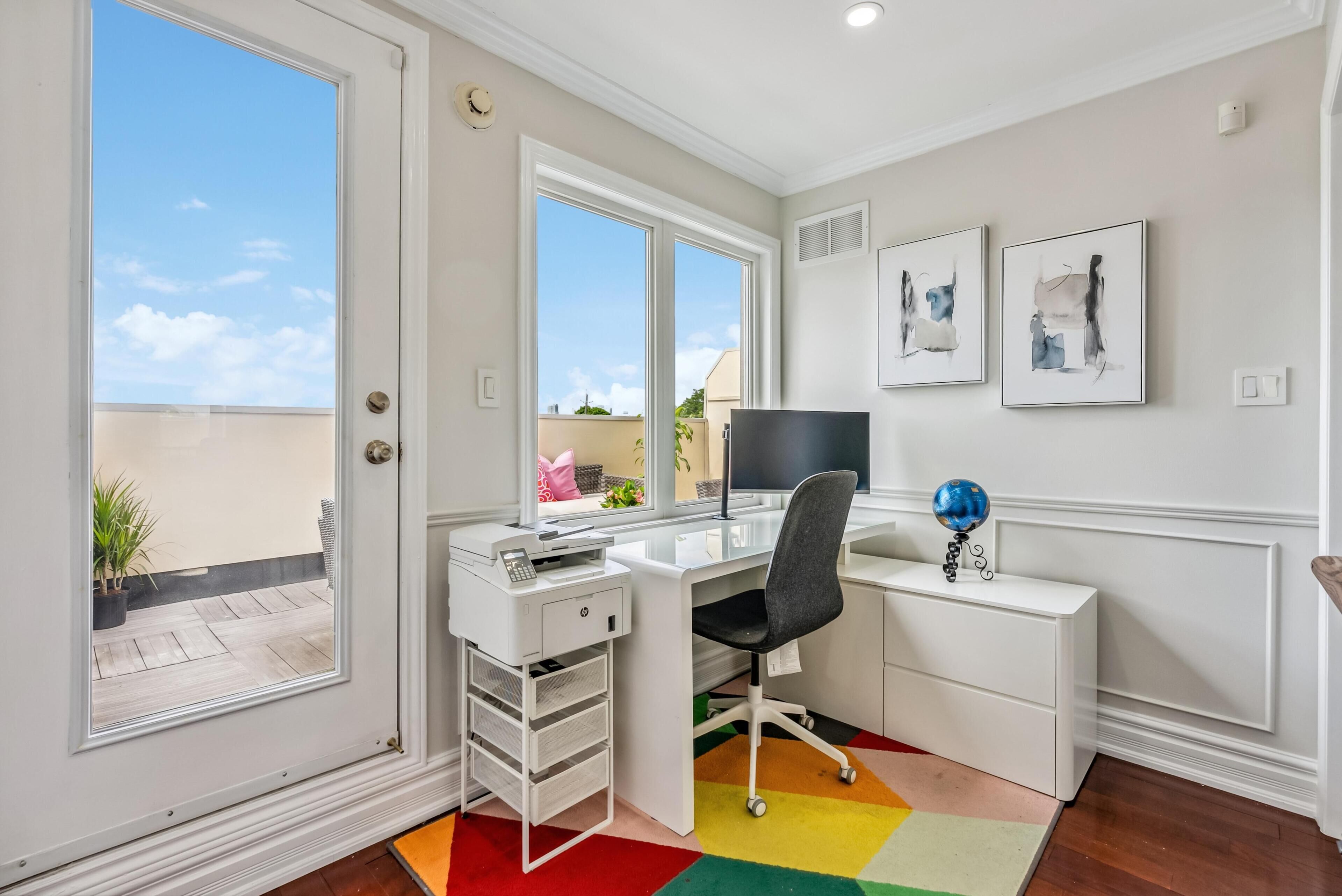 Un espace de bureau moderne comprenant un bureau, une chaise, une imprimante et une œuvre d’art accrochée au mur.