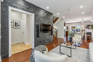 A modern living room with a stone accent wall, a fireplace, and a staircase leading to an upper level. - Luxurious townhome ideal for families, business travelers, and long stays. (Toronto)