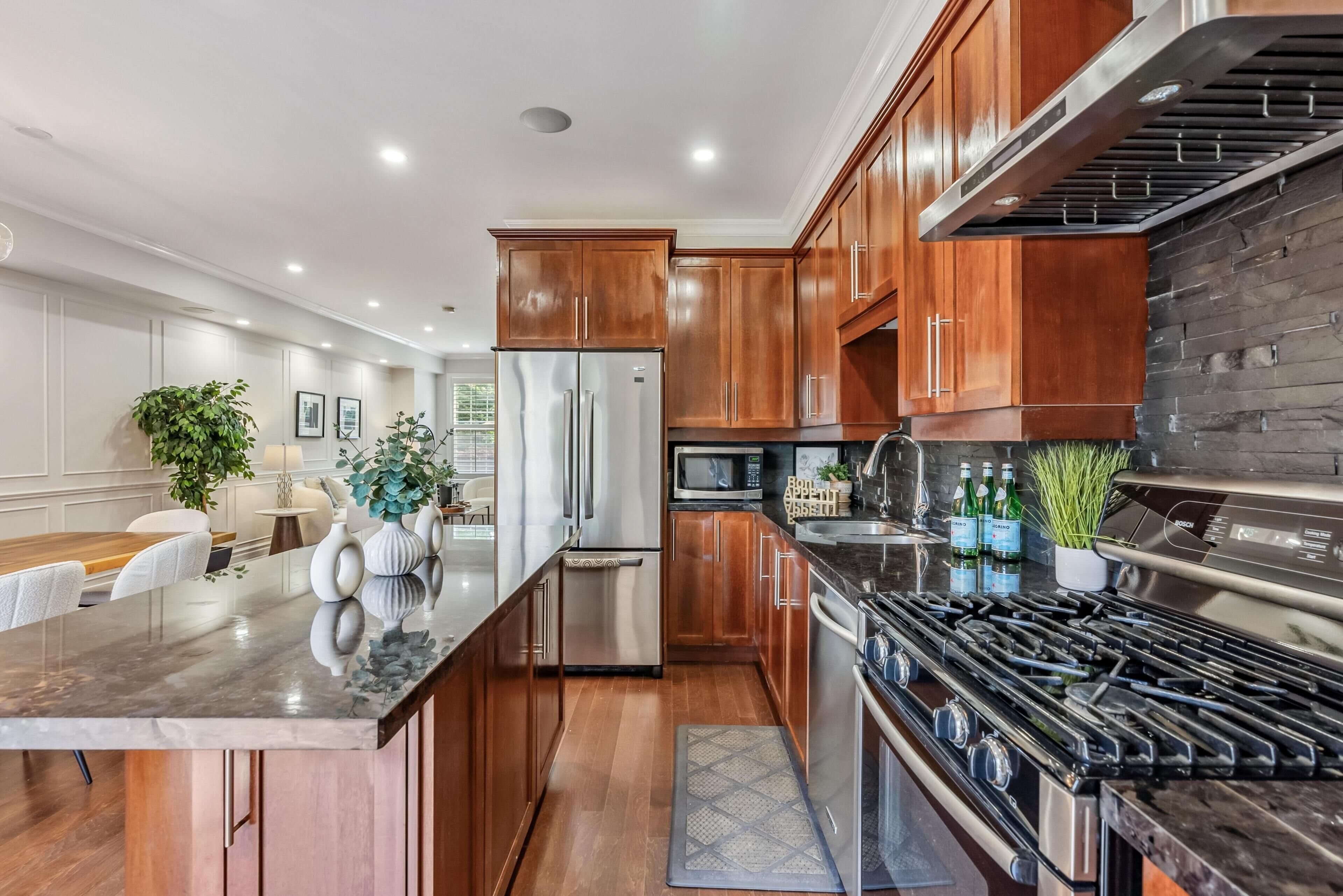 Una cocina moderna con armarios de madera, electrodomésticos de acero inoxidable y encimera de granito.