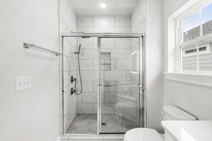 Ein modernes Badezimmer mit einer Duschkabine, einer Toilette und einem Fenster.