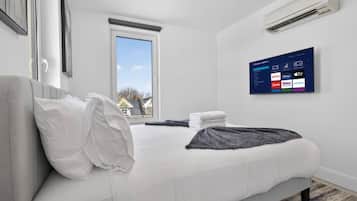 Queen bedroom with Roku TV, fresh linens and natural light.