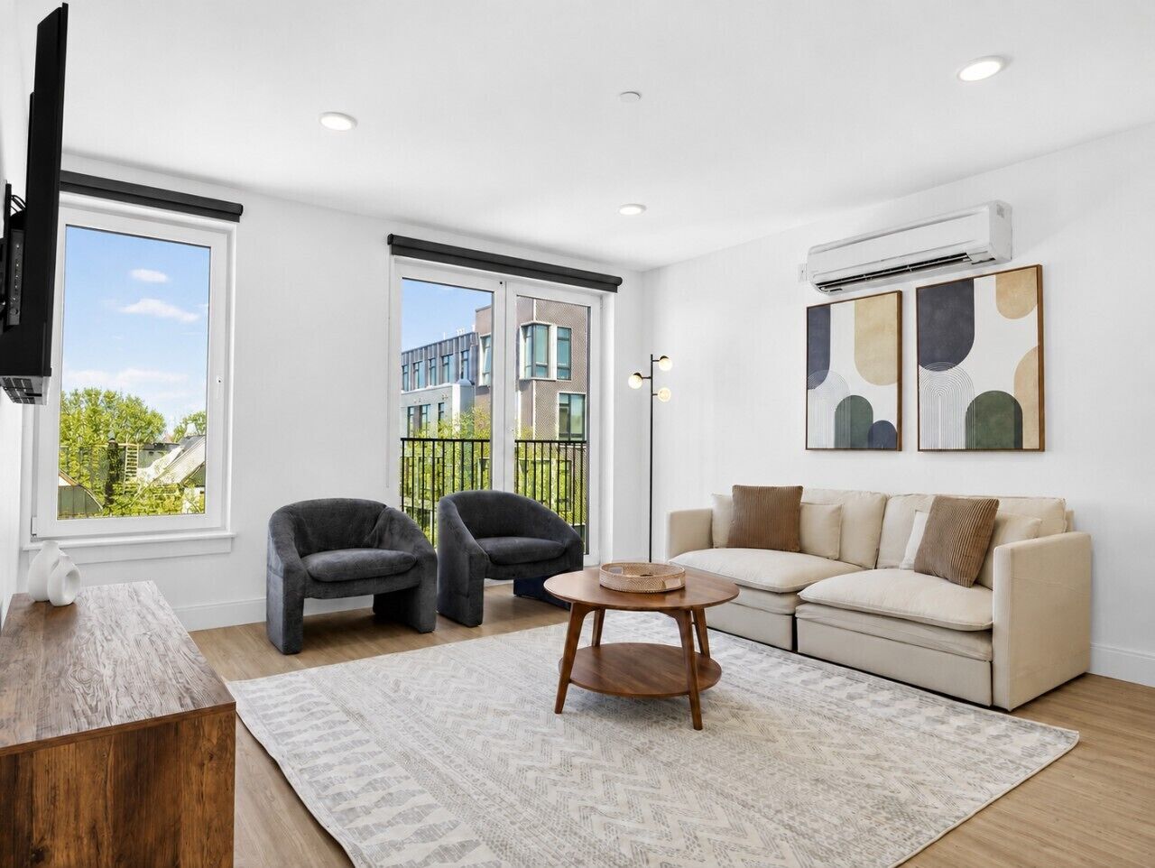 A modern living room with a sofa, two armchairs, a coffee table, and a TV.