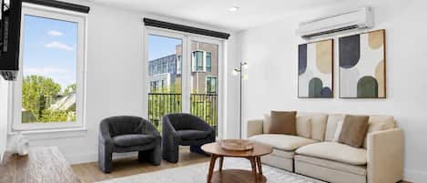 A modern living room with a sofa, two armchairs, a coffee table, and a TV.