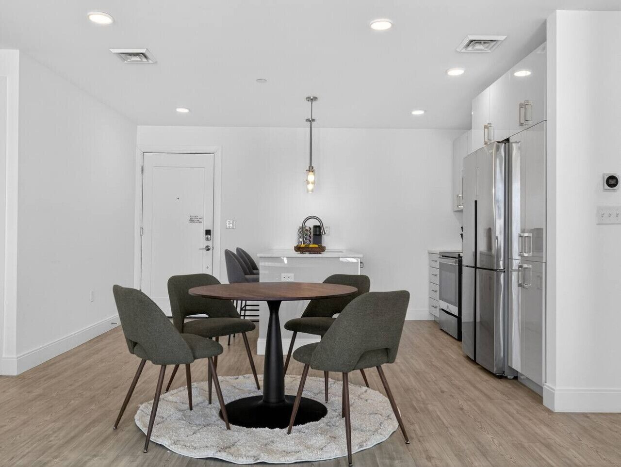 A modern kitchen with a central island, white cabinets, and stainless steel appliances.
