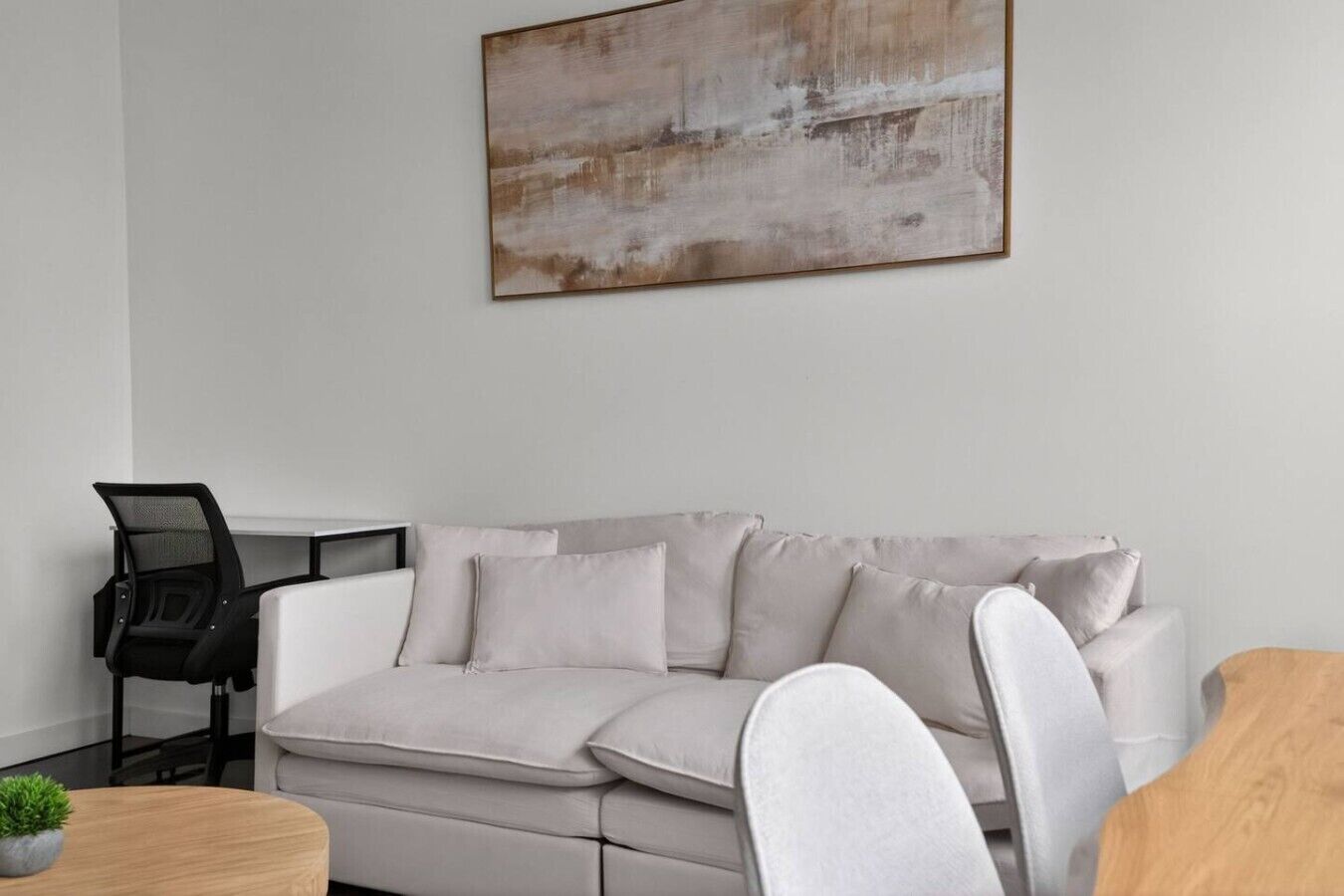 Un soggiorno moderno con un divano, un tavolino da caffè e un quadro appeso al muro.