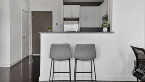 Une cuisine moderne avec un coin bar, deux tabourets de bar et un réfrigérateur.