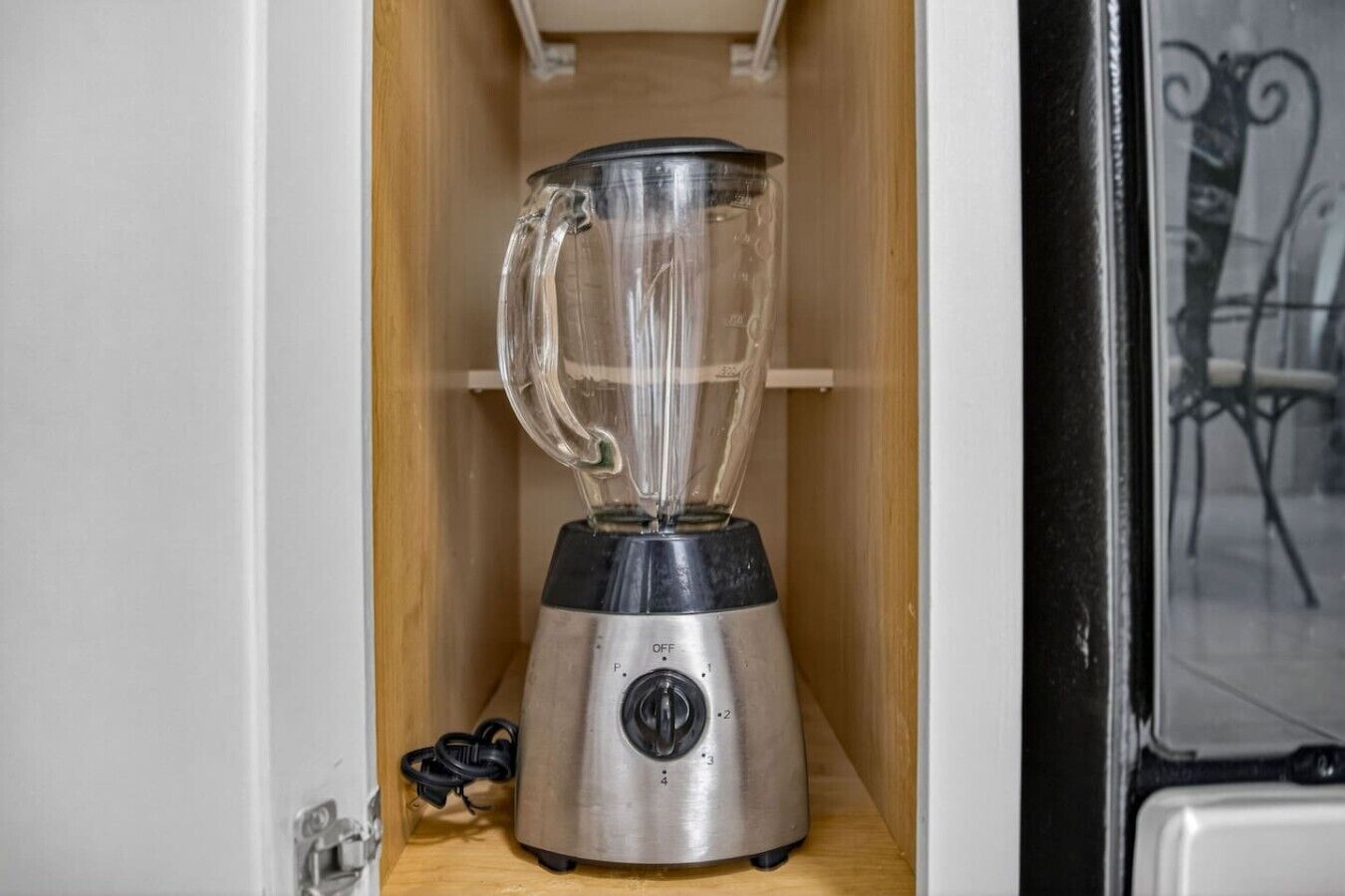 A compact kitchen with a built-in blender on a wooden shelf.
