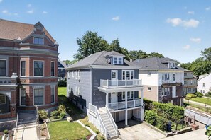 A residential area with multi-story houses, including a two-story house with a balcony and a garage. - 3BR Boston Stay | 2 Balconies + Views (Boston)