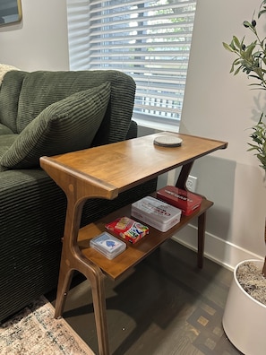 A wooden side table with a shelf holding board games and a small plant. - Spacious 2 unit Gordon SQ building! 2 bed 2 bath! 2 kitchens! 2 living rooms! (Cleveland)