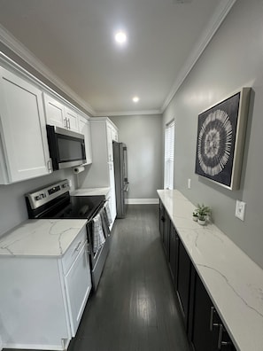 A kitchen with white cabinets, a black microwave, a stainless steel refrigerator, and a marble countertop. - Spacious 2 unit Gordon SQ building! 2 bed 2 bath! 2 kitchens! 2 living rooms! (Cleveland)
