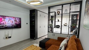 Un soggiorno moderno con un divano componibile, un tavolino in legno, una TV a parete e una mensola decorativa con piante.