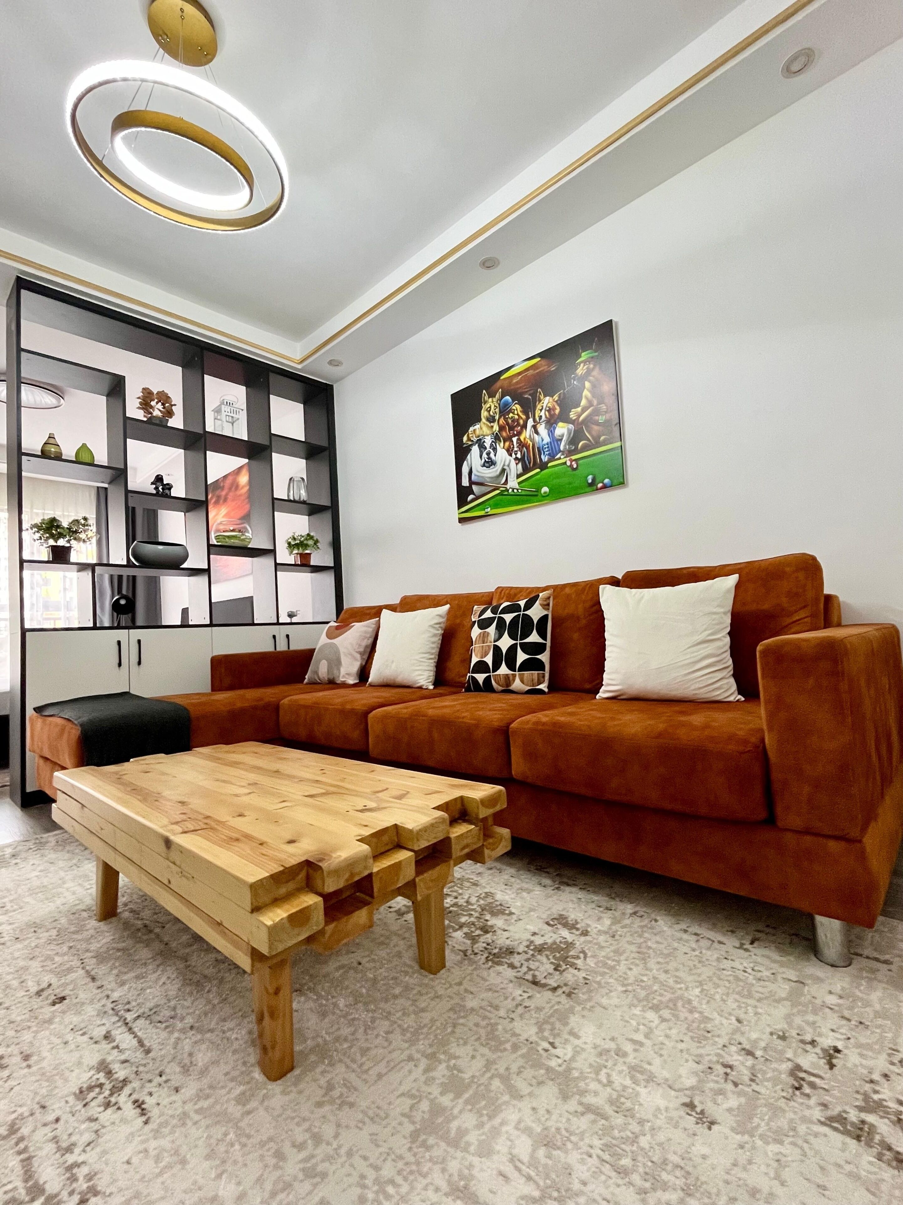 Ein modernes Wohnzimmer mit einem braunen Sofa, einem Holztisch und einem Wandbild.