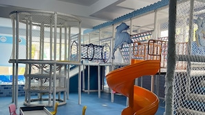 Un'area giochi per bambini con scivolo, strutture di arrampicata e sedute imbottite.