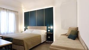 Une chambre d’hôtel avec un lit, un canapé, un bureau et une table de chevet.