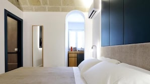 Une chambre d’hôtel avec un lit, une armoire et une vue sur l’extérieur, visible à travers une arche.