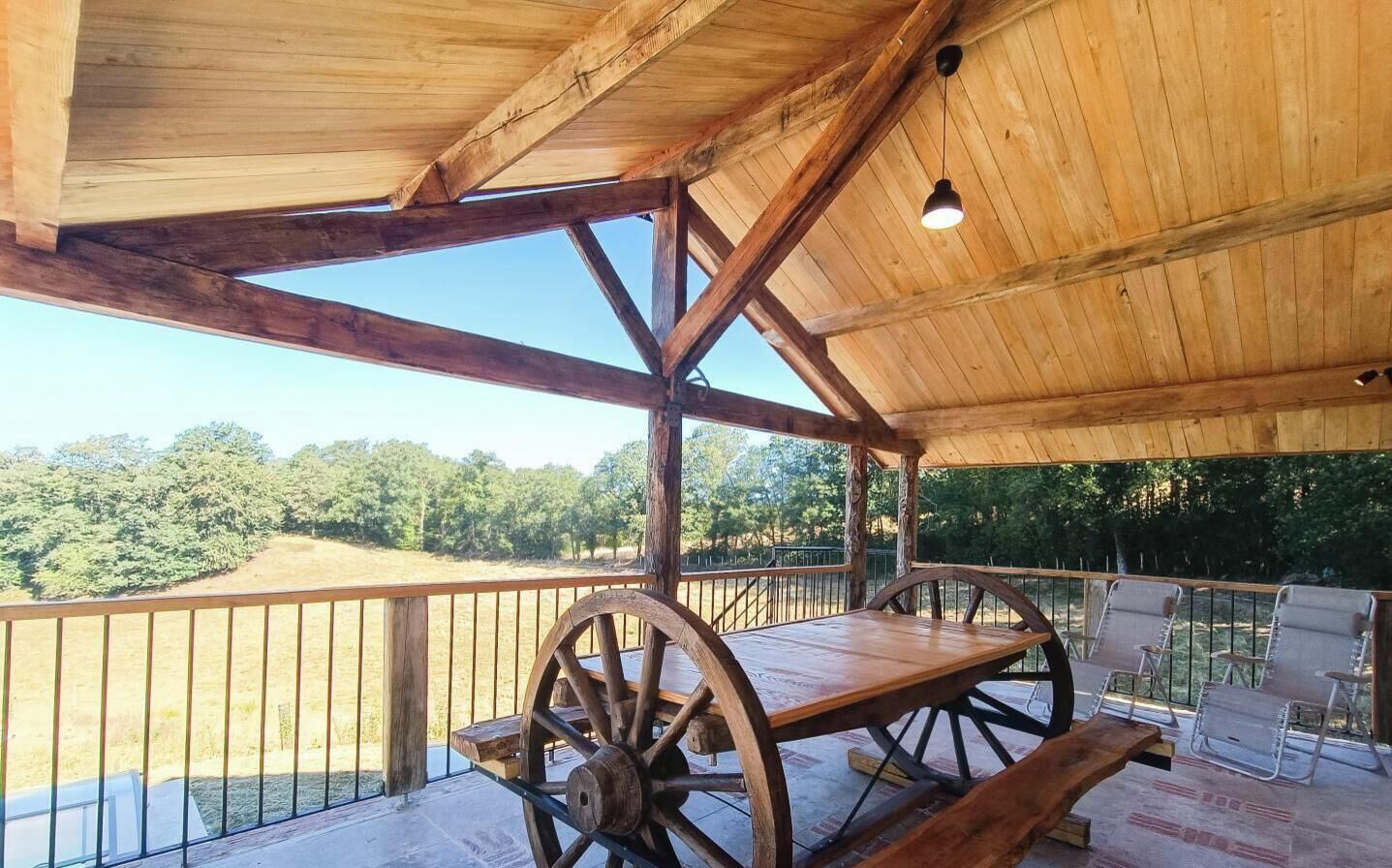 A wooden deck with a picnic table and chairs, overlooking a grassy area.