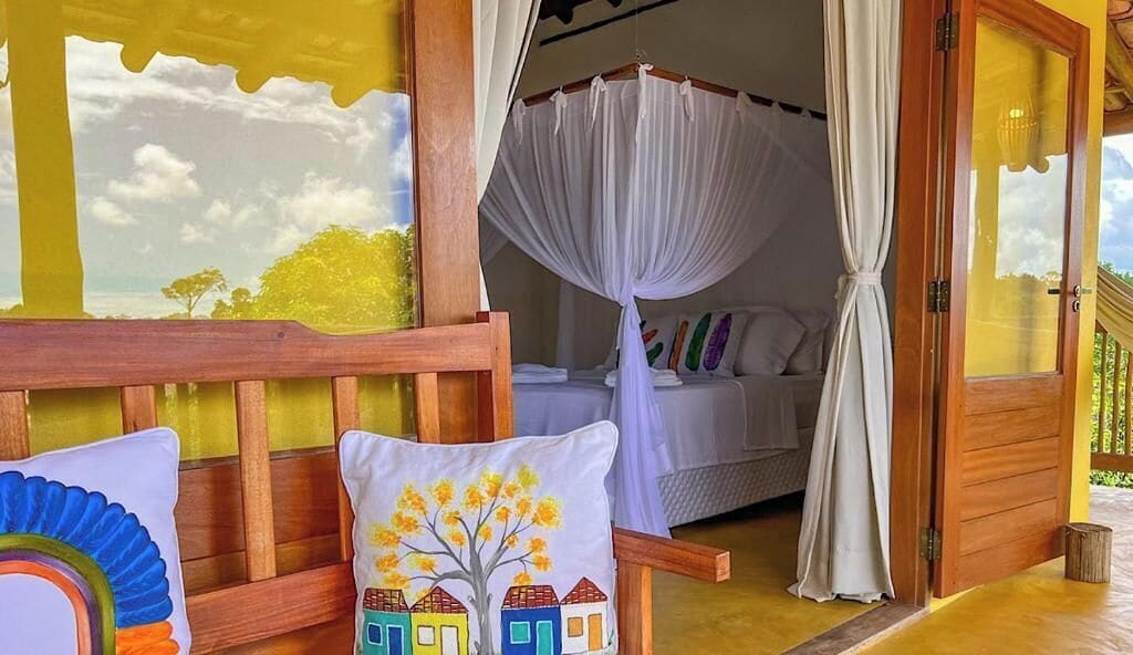 Una habitación con una cama, un banco de madera y vistas al exterior.