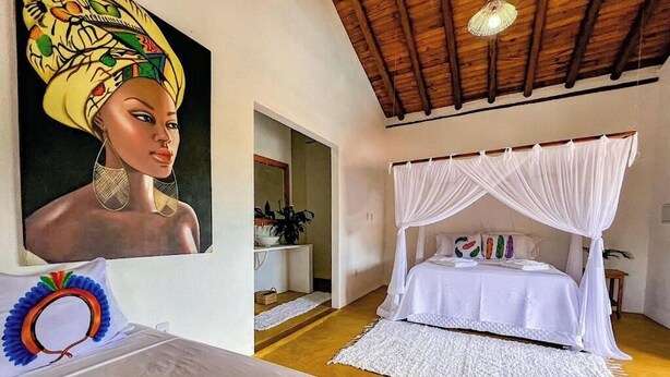 Un dormitorio con cama con dosel, un cuadro en la pared y techo de madera.