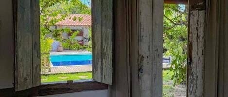 A room with a bed, a window, and a view of a pool.