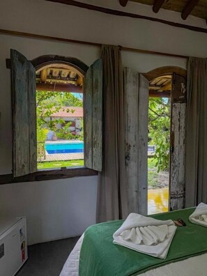 Una habitación con cama, ventana y vista a una piscina.