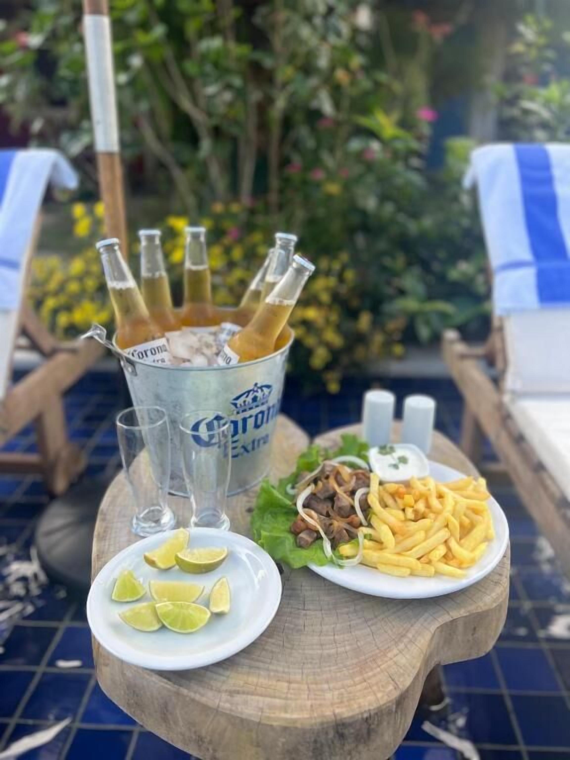 Una mesa de comedor con un plato de comida, una jarra de cerveza y un plato de gajos de limón.