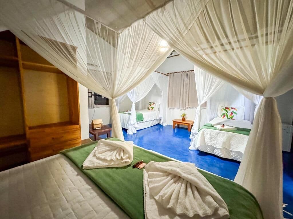 A room with a bed, a green mat, and a canopy bed with white bedding.
