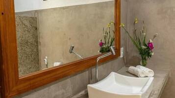 Un bany amb un mirall gran, un lavabo blanc i dues tovalloles arremolinades al taulell.