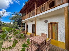 A two-story building with a balcony, outdoor seating area, and a garden.