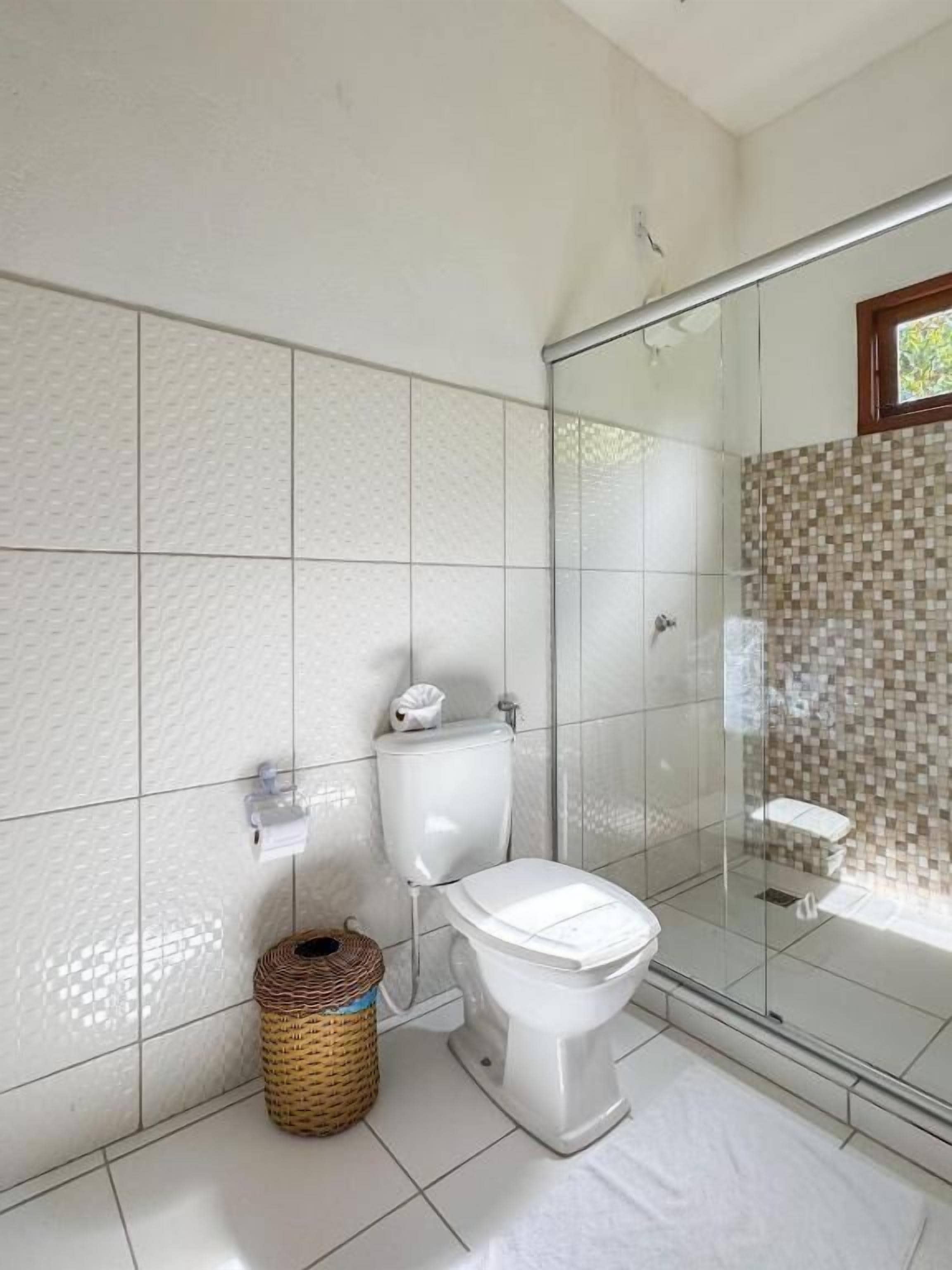 A bathroom with a toilet, a glass shower enclosure, and a tiled wall.
