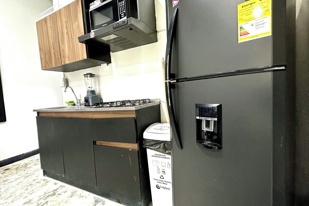 A modern kitchen with a refrigerator, stove, microwave, and a water dispenser.